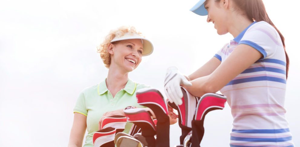 Low angle view of happy female golfers talking against clear sky
