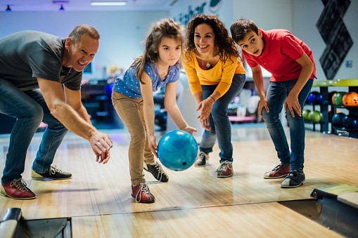Smiling young couple bowling with their children