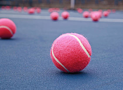 many pink tennis balls on a blue court